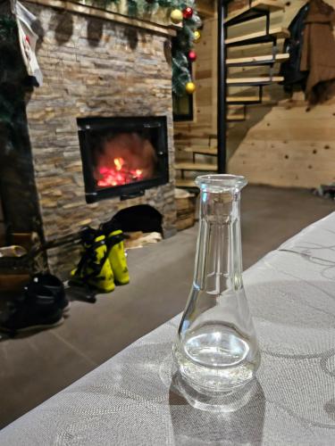 a glass bottle sitting on a table in front of a fireplace at Šumska vila in Šljivovica