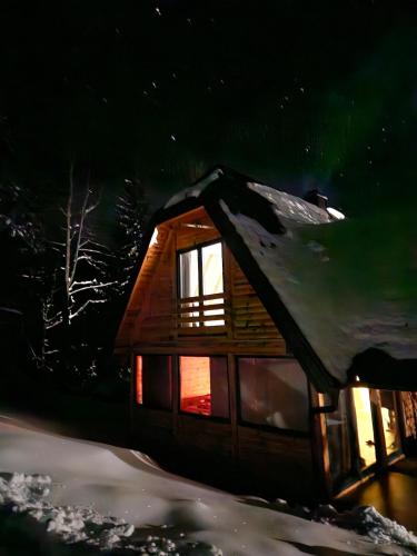 a log cabin with snow on the roof at night at Šumska vila in Šljivovica