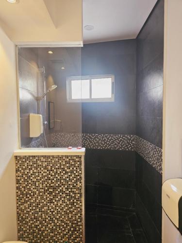 a bathroom with a shower with black walls and a window at Pura vida apartments in Quepos