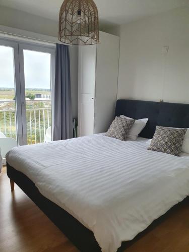 a bedroom with a large white bed with a balcony at Residentie Majestic in Middelkerke