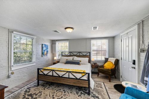 a bedroom with a bed and a chair and windows at Downtown Cottage Hammond, Pool, Hot Tub, King Bed in Hammond