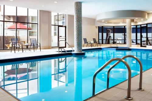 a pool in a hotel with tables and chairs at Four Points by Sheraton Mississauga Meadowvale in Mississauga