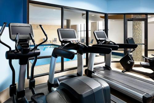 a gym with three cardio machines and a swimming pool at Four Points by Sheraton Mississauga Meadowvale in Mississauga