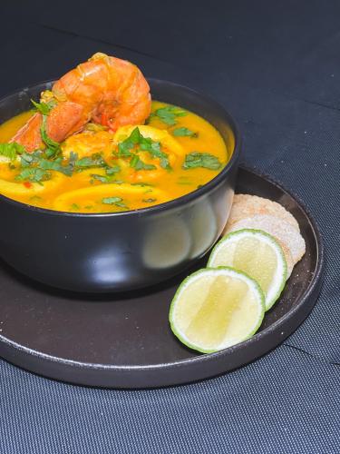 a bowl of seafood soup with a slice of bread and lime at Hotel Vip La Guaira in Macuto