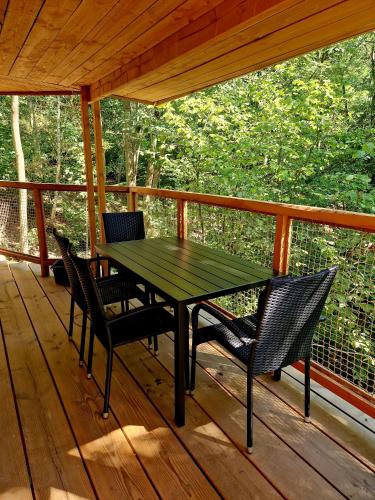 a green table and chairs on a wooden porch at Les Cabanes du Beau Vallon in Profondeville