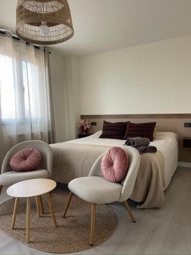 a bedroom with a large bed with two chairs at Casa de la luz in Peñafiel