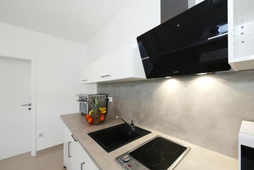 a kitchen with a sink and a microwave at Apartments ROSINI, 300m from the beach with shared tavern and bikes, Nin in Nin