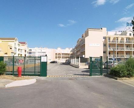 Une rue vide dans un parking avec des bâtiments dans l'établissement Apt de charme 4 pers, vue port, location idéale, à Gruissan