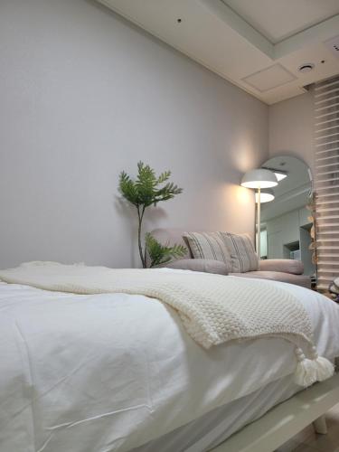 a bedroom with a large white bed and a plant at Bara H 고양 킨텍스역 종합운동장 in Goyang