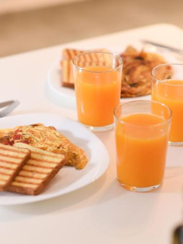 a table with a plate of food and two glasses of orange juice at Basil Tree Stonehouse in Flomokhórion