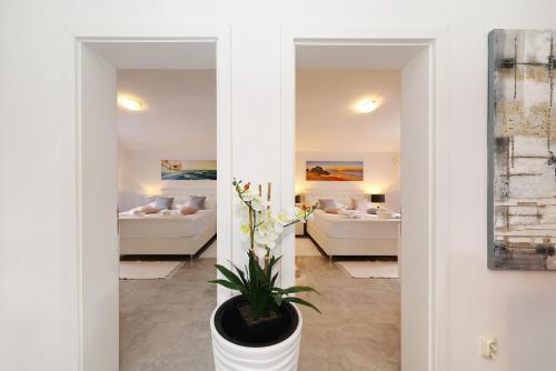 a living room with two beds and a potted plant at Apartments ROSINI, 300m from the beach with shared tavern and bikes, Nin in Nin