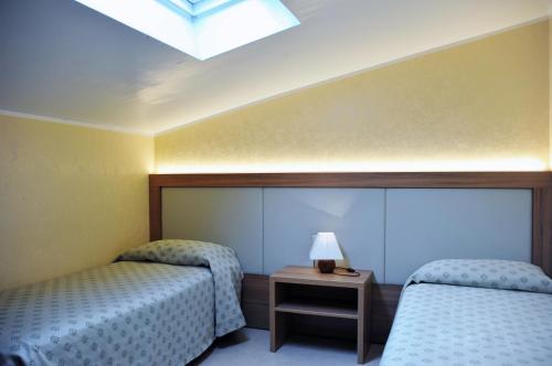 a room with two beds and a lamp on a table at Residence Primavera in Bardolino