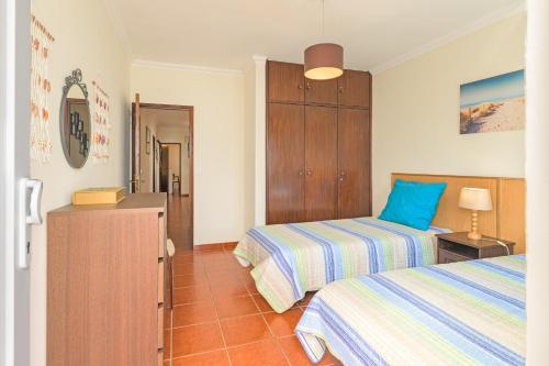 a bedroom with two beds and a dresser in it at Milfontes Beach House in Vila Nova de Milfontes