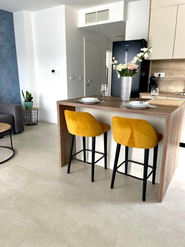 a kitchen with a wooden table and two yellow chairs at Sandi Hvar Apartments in Hvar