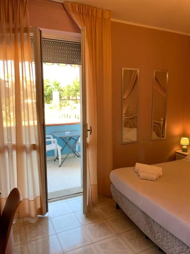 a bedroom with a bed and a door to a patio at Hotel Riva Etrusca in Marina di Bibbona