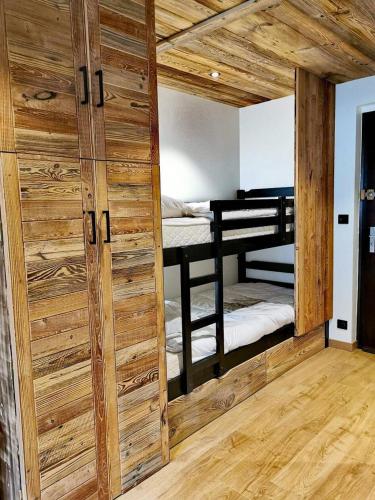 Cette chambre comprend 2 lits superposés et une porte en bois. dans l'établissement Résidence Eden Roc I - Très beau studio, rénové et pratique d'utilisation MAE-1303, aux Gets