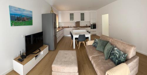 a living room with a couch and a tv and a kitchen at Jardins do Barão in Leiria