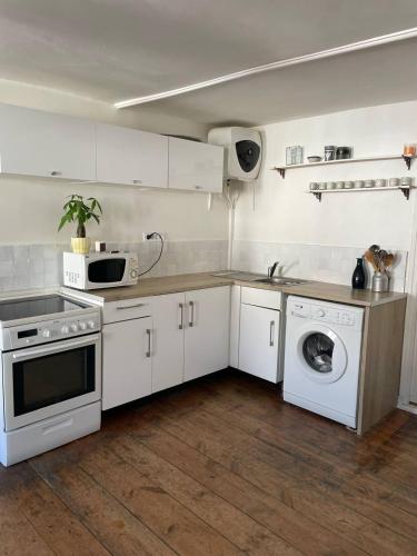 a kitchen with white cabinets and a washer and dryer at Nid cosy au cœur de Palais in Le Palais