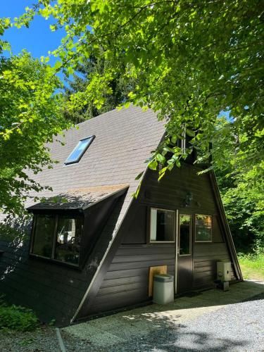 a brown house with a gambrel roof with a window at Forest Lodge Durbuy in Durbuy