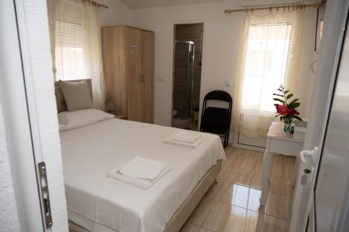a bedroom with a white bed and a bathroom at apartmani DENI in Donji Štoj