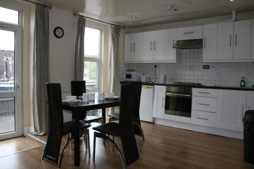 una cucina con armadi bianchi, tavolo e sedie di Marble Arch Flats a Londra