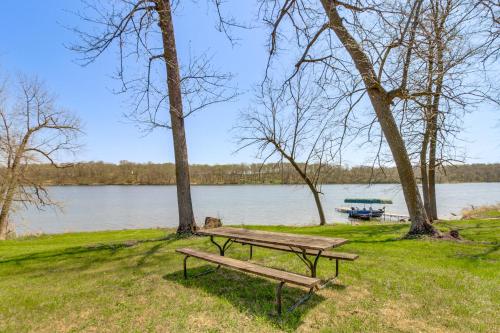 a picnic table in the grass next to a lake at Lakefront Family Home with Boat Dock in Underwood in Battle Lake