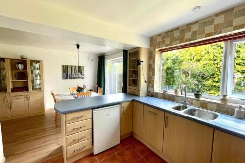 a large kitchen with a sink and a window at 4-Bedroom Retreat in Staines with Private Garden & Easy Parking in Staines