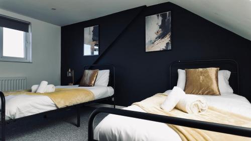 two beds in a room with black walls at Modern Comfort 4BR Home for 10 in North Weald