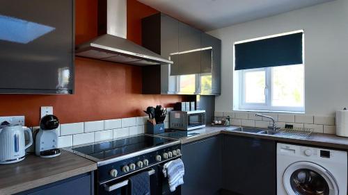 a kitchen with a sink and a washing machine at Modern Comfort 4BR Home for 10 in North Weald