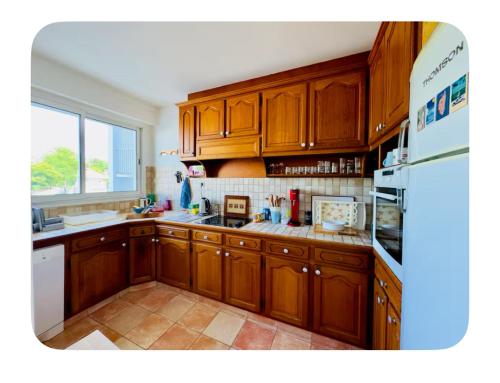 une cuisine avec des armoires en bois et un réfrigérateur blanc dans l'établissement Vacances en Famille face mer - plage à Pontaillac, à Royan