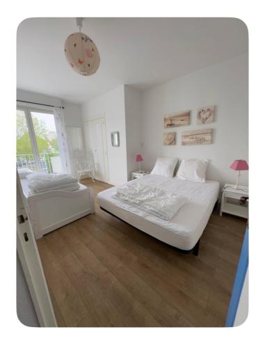 - une chambre blanche avec 2 lits et une table dans l'établissement Vacances en Famille face mer - plage à Pontaillac, à Royan