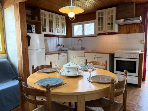 - une cuisine avec une table en bois, des assiettes et des verres à vin dans l'établissement Résidence C21-ile Grande - Jolie Maison de pêcheur au cœur de l'Ile Grande MAE-1293, à Pleumeur-Bodou