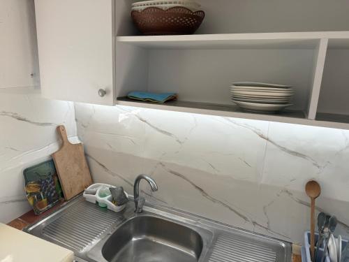 a kitchen sink with dishes on a shelf above it at Villa Gjoka in Velipojë