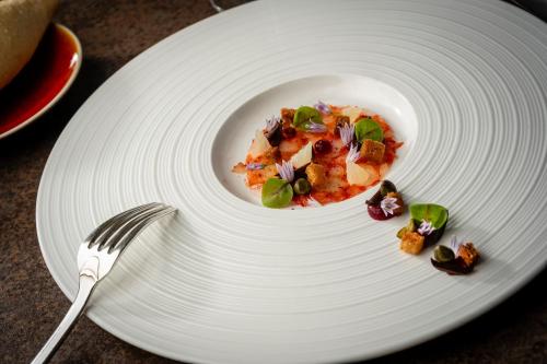 a white plate with food on it with a fork at Hôtel Beau Rivage Condrieu in Condrieu