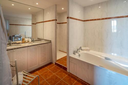 a bathroom with a tub and a sink and a counter at Hôtel Beau Rivage Condrieu in Condrieu