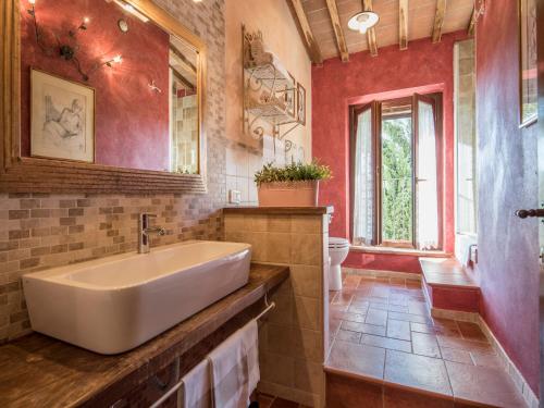 ein Badezimmer mit einem weißen Waschbecken und roten Wänden in der Unterkunft Appartamento La Roccaia in San Gimignano