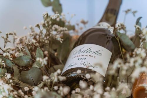 a bottle of wine in a field of flowers at La Parenthèse Cosy Jacuzzi & Charme in Aubenas