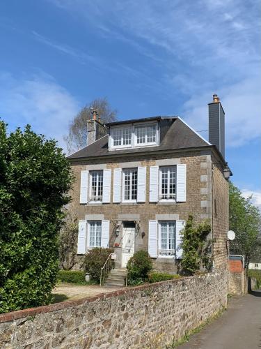 une ancienne maison en briques avec un mur en pierre dans l'établissement Family home Cour du Louvre, à Saint-Sever-Calvados