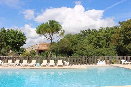une piscine avec des chaises longues et une clôture dans l'établissement Le Vignal, à Monflanquin