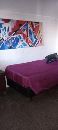 a bed in a room with a purple blanket at La casita in Mendoza