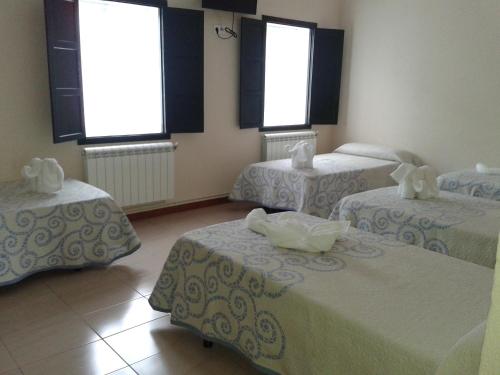 three beds in a room with three windows at Pensión Mar in Portomarin