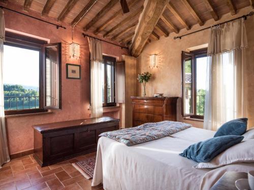 a bedroom with a bed and a desk and windows at Appartamento La Roccaia in San Gimignano