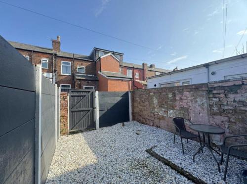a patio with two chairs and a table and a fence at Levenshulme House - 2 Bedroom - Sleeps 6 - Free Parking & WiFi in Manchester
