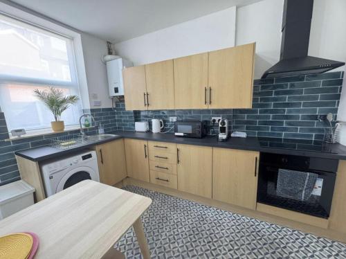 a kitchen with wooden cabinets and a washer and dryer at Levenshulme House - 2 Bedroom - Sleeps 6 - Free Parking & WiFi in Manchester