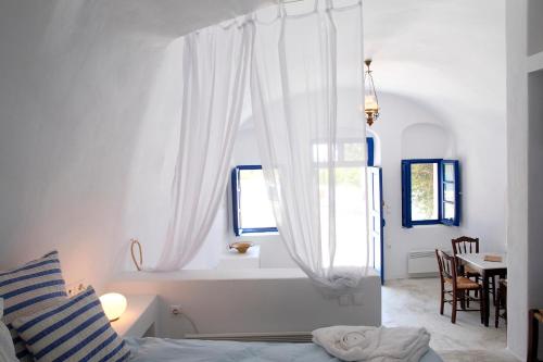 a white bedroom with a bed and a window at Aghios Artemios Traditional Houses in Imerovigli