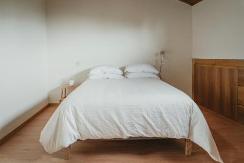a bedroom with a white bed with two pillows at Abrigos do Castelo in Carvalho de Rei