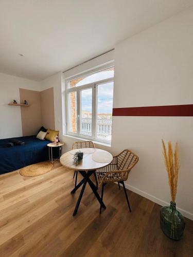 Cette chambre comprend une table, un lit et une fenêtre. dans l'établissement Yogi - Studio rénové - Centre, à Coudekerque-Branche
