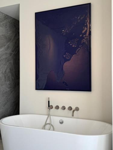 a bath tub in a bathroom with a painting on the wall at TEAM bnb in De Koog