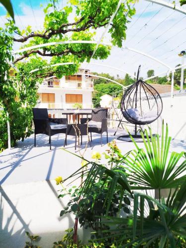 a patio with a table and chairs and plants at Apartmani Ruža in Zaton
