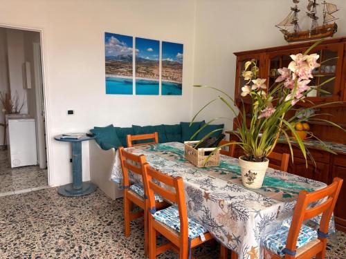 a dining room table and chairs with a table and flowers at all ombra dei pini in La Caletta